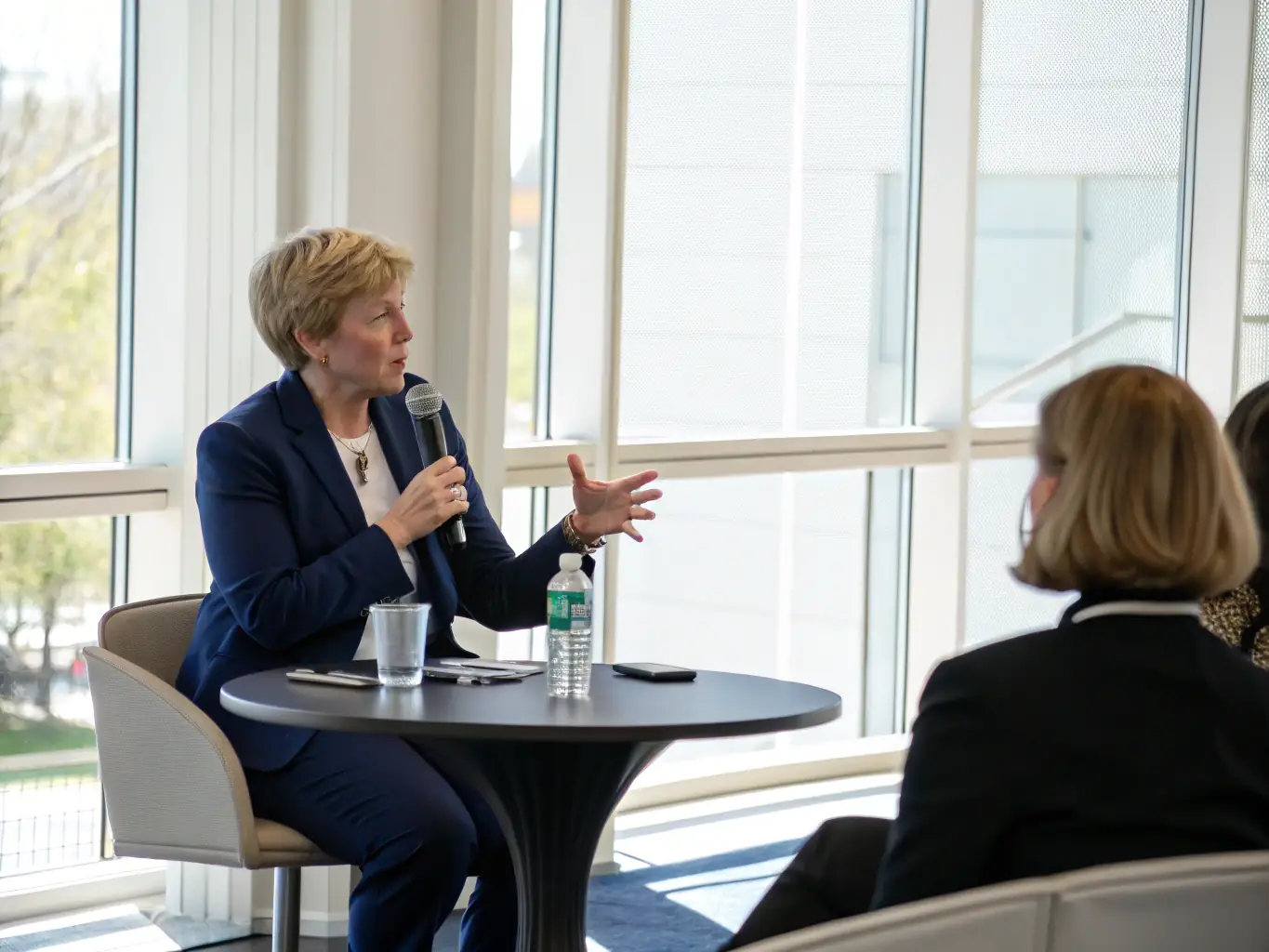 An empowering image of a confident woman speaking at a leadership conference, representing the Women in Leadership Coaching service offered by oceanstorm.fun.
